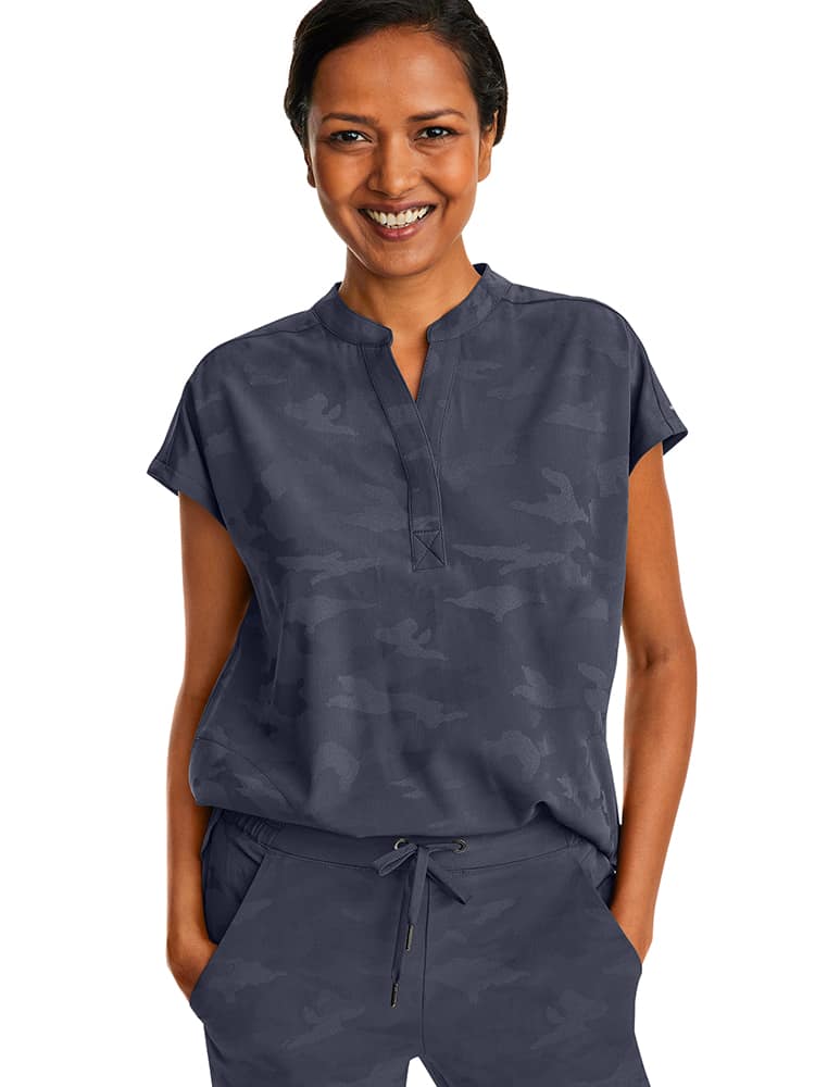 A young female Nurse Practitioner wearing a Products Purple Label Women's Journey Camo Top in Pewter size Small featuring a modern fit.