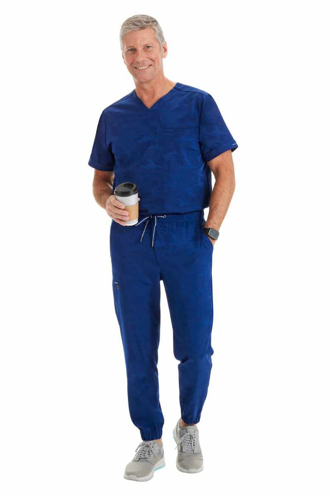 A male LPN wearing a Purple Label Men's Jack Camo Scrub Top & the matching Men's Drew Camo Jogger in Navy.