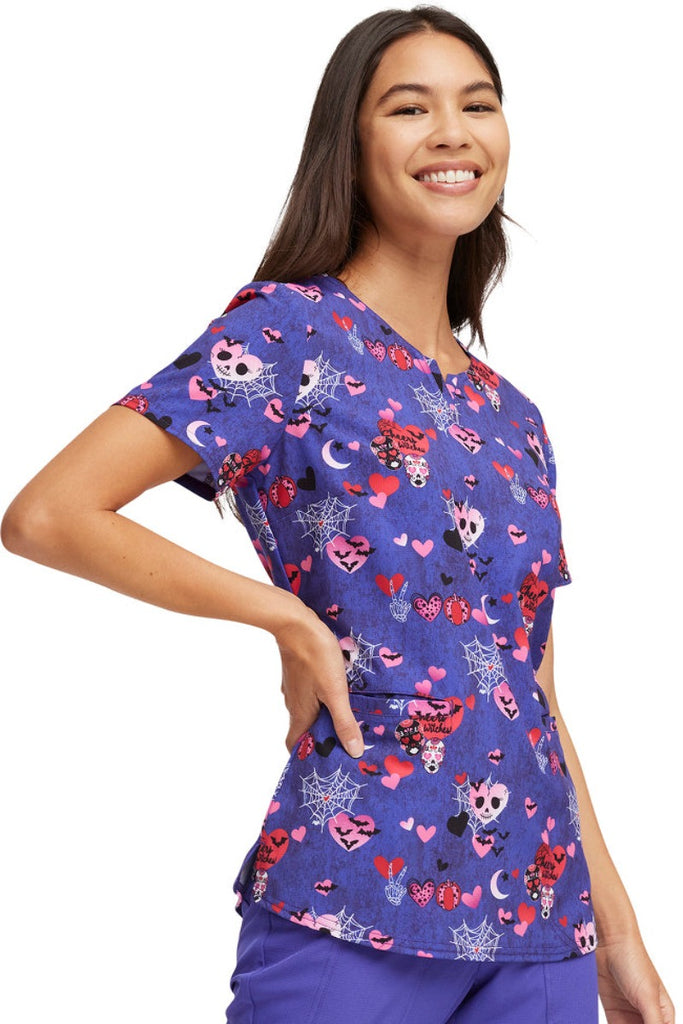 An image of the side of the HeartSoul Women's V-Neck Halloween Printed Scrub Top in "Cheers Withces" featuring side slits for additional mobility.