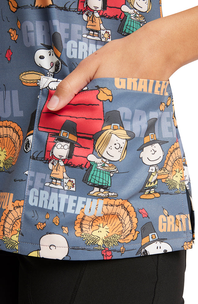 A close up shot of the left side front patch pocket on the Tooniforms Women's V-Neck Thanksgiving Printed Scrub Top in "Grateful Snoopy".