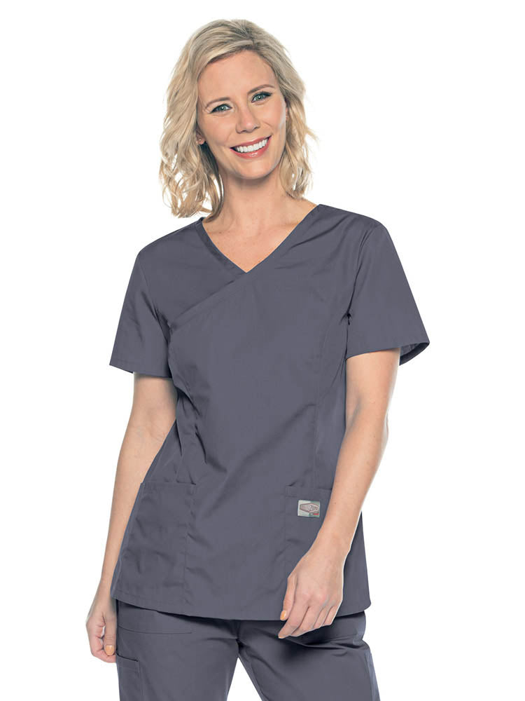 A young female Medical Assistant wearing a Landau ScrubZone Women's Mock Wrap Top in Steel size Small featuring a modern tailored fit.