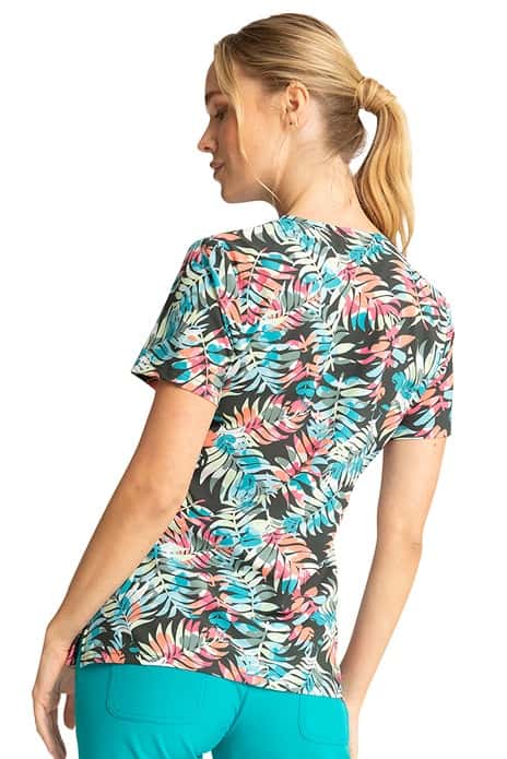 A young Home Care Registered Nurse wearing a Cherokee Women's Mock Wrap Print Top in "Loving Tropic" featuring side vents for ease of movement.