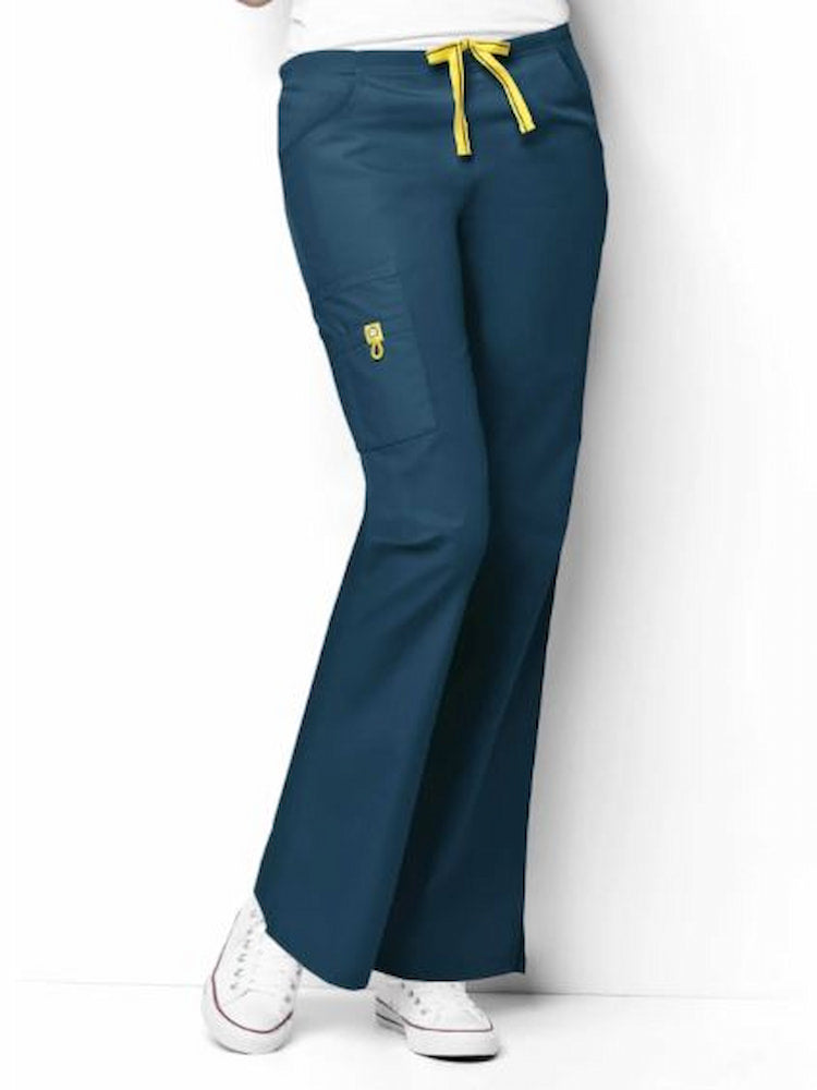 A young female Healthcare Professional wearing a WonderWink Women's Romeo Cargo Scrub Pant in Caribbean size XXS Petite featuring a flat front with convertible signature yellow twill tape drawstring and back elastic waistband.