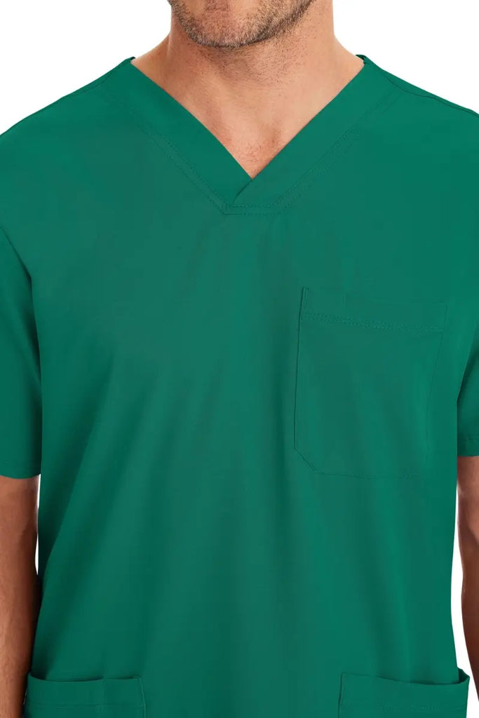 A young male Brain Surgeon wearing an HH-Works Men's Matthew V-Neck Scrub Top in Hunter Green featuring a single chest pocket on the wearer's left side.