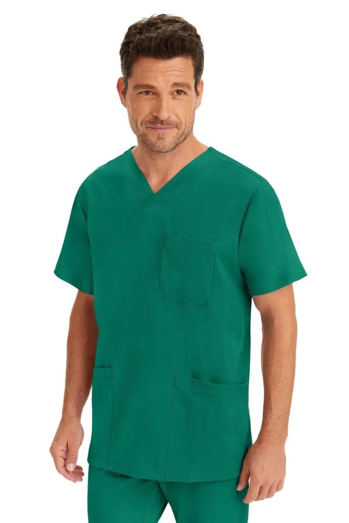 A male Surgeon wearing an HH-Works Men's Matthew V-Neck Scrub Top in Hunter Green featuring a unique 4 way stretch fabric.