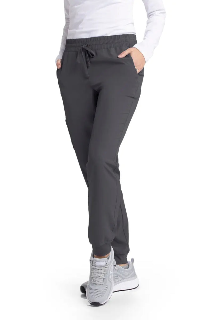 A young female Pharmacy tech wearing a pair of the Skechers Women's Theory Scrub Joggers in Pewter size medium featuring two front slanted pockets.