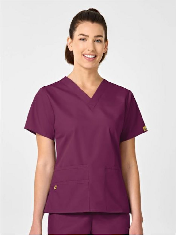 A young female LPN wearing a WonderWink Origins Women's Bravo V-neck Scrub Top in Wine size large featuring a soft poly/cotton blend.