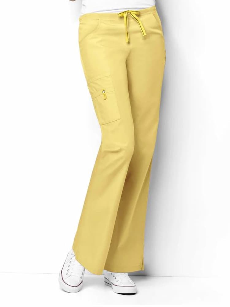 A young female Medical Assistant wearing a pair of the WonderWink Origins Women's Romeo Cargo Scrub Pants in Yellow size 3XL Petite featuring a total of 6 pockets.