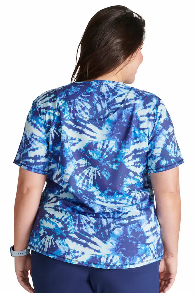 A young female Pediatric Nurse wearing a Cherokee Women's V-neck Printed Scrub in "Tie Dye Tranquility" size XL featuring a center back length of 26".
