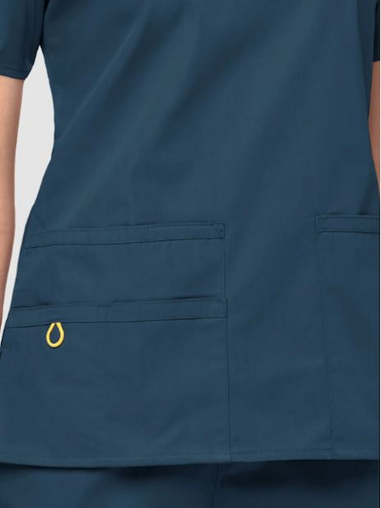 An up close image of the two lower pockets including one WonderWink signature triple pocket with hidden mesh pocket & signature ID bungee loop on the WonderWink Origins Women's Bravo V-neck Scrub Top in Caribbean Blue size 2XL.