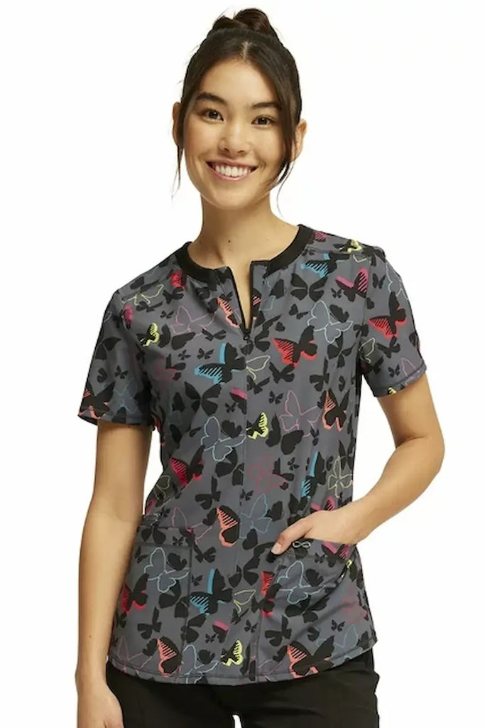 A young female Pediatric Nurse wearing a Cherokee Infinity Women's Round Neck Printed Scrub Top in "Brilliant Butterflies" size small featuring a contemporary fit.