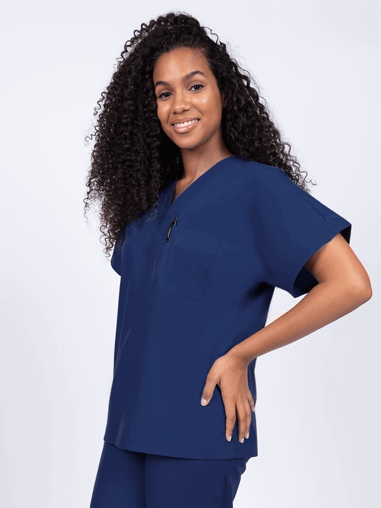 Young female healthcare worker wearing a Luv Scrubs Unisex Single Pocket V-Neck Scrub Top in navy with one chest pocket and a pen slot.