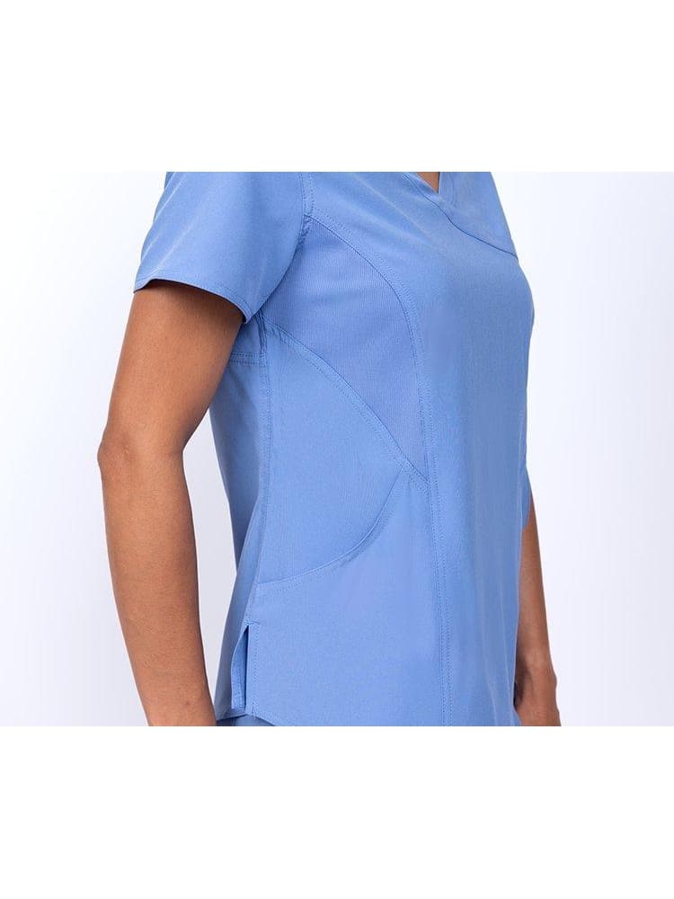 An up close i mage of a female Physician's Assistant wearing a Meraki Sport Women's Mock Wrap Scrub Top in Ceil Blue featuring 2 curved front pockets for all your on the job storage needs.