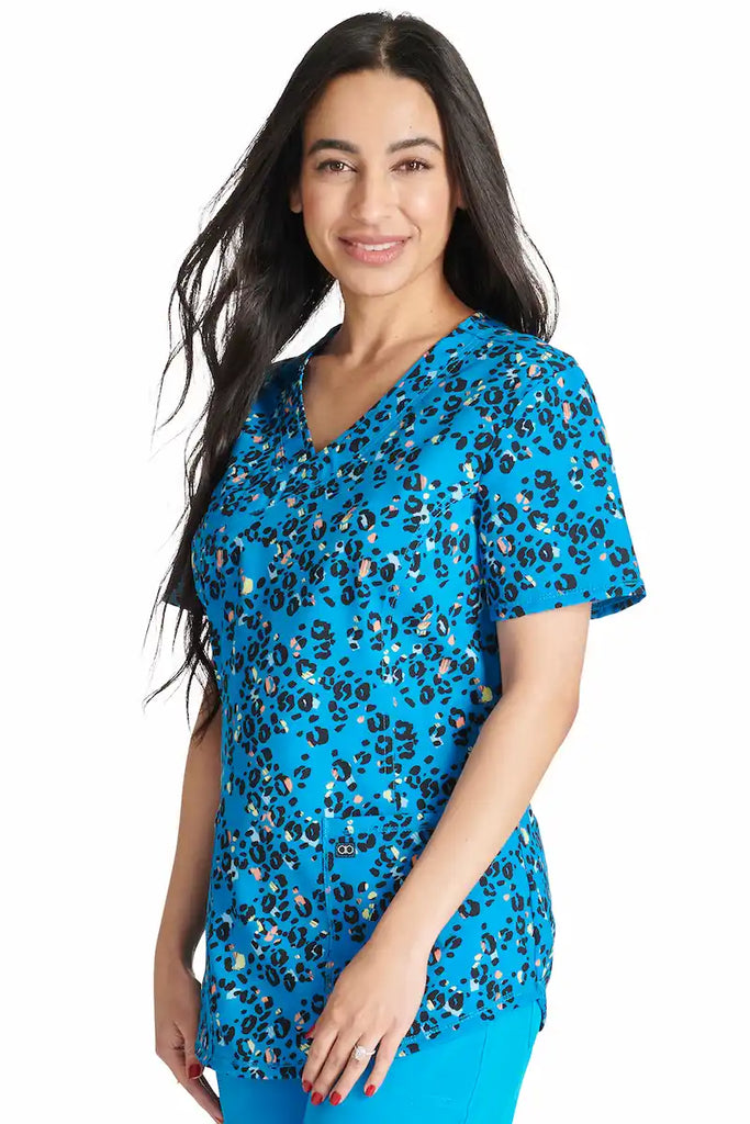 A young female Neonatal Nurse wearing a Cherokee Women's V-neck Printed Scrub Top in "Leopard Pops" size XL featuring front princess seams for a flattering fit.