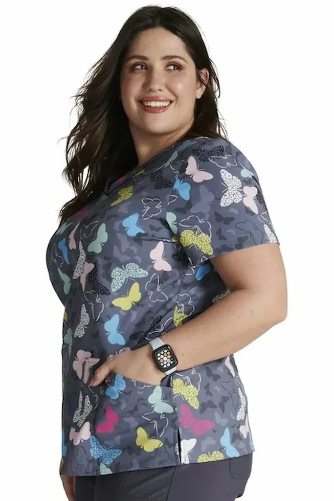 An image of the side of an Oncology Nurse wearing a "Cherokee Women's V-neck Print Scrub Top in "Wing It Up" size XL featuring four total pockets for ample storage space.