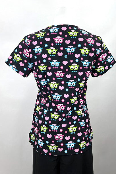 An image of the Revel Women's V-neck Print Scrub Top in "Owl Heart" size Small featuring side slits for additional range of motion throughout the day.
