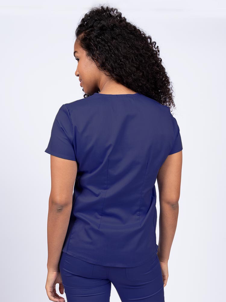 Woman wearing an Epic by MedWorks Women's Blessed Scrub Top in navy with a pleated back for a flattering fit.