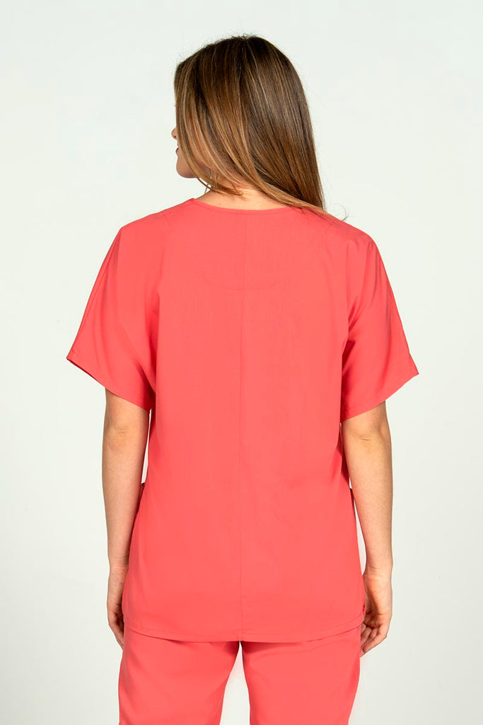 A young female Nursing Assistant wearing an Epic by MedWorks Unisex V-neck Scrub Top in Coral size large featuring a center back length of 27.5".