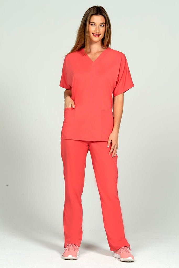 A female Radiologic Technologist wearing an Epic by MedWorks Unisex V-neck Scrub Top in Coral size small featuring a streamline fit for a tailored look without losing mobility.
