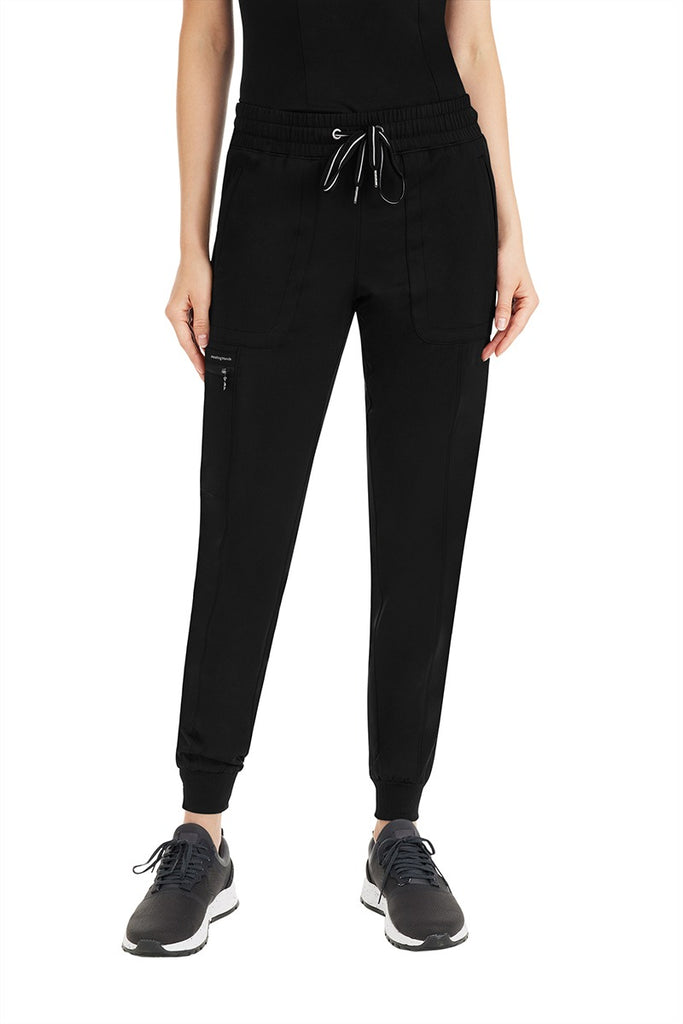 A female Nursing Assistant wearing a pair of Women's Aspen Jogger Scrub Pants from Purple Label by Healing Hands in "Black" size Medium featuring a 2x2 rib knit waistband & leg cuffs.