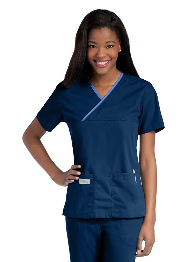 Young lady wearing an Urbane Essentials Women's Crossover Scrub Top in "Navy/Ceil" featuring a unique crossover neckline for a flattering fit.