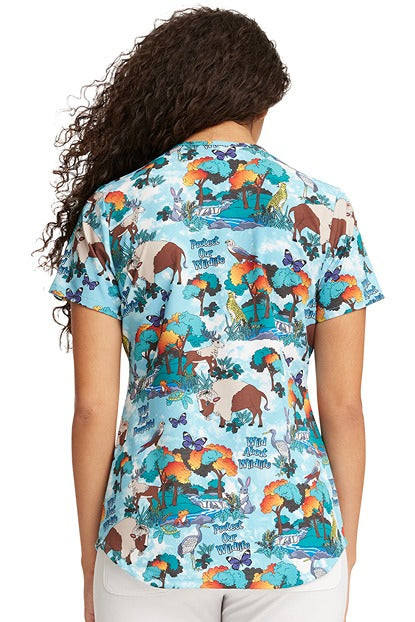 A young female CNA wearing a Cherokee Women's V-Neck Print Scrub Top in "Wildlife Sanctuary" size Medium featuring a center back length of 28".