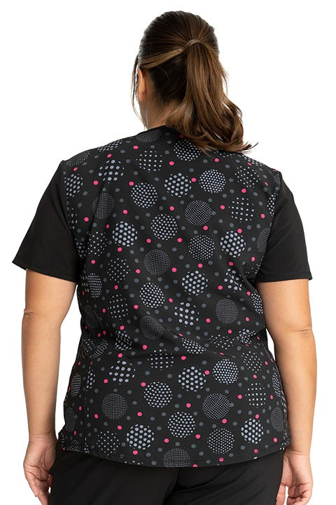 A young female nurse wearing a Cherokee Tooniforms Women's Stylized V-Neck Print Top in "Minnie Spotlight" featuring a curved hem.
