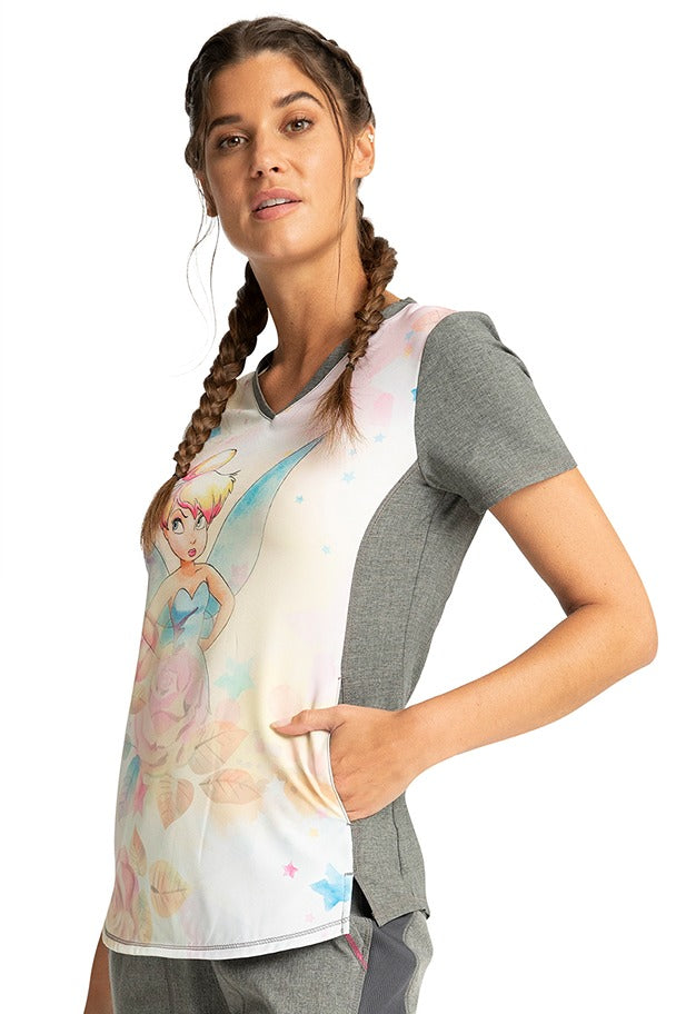 A young LPN wearing a Tooniforms Women's V-Neck Print Top in "Fairy Wings" featuring 2 in-seam front pockets.