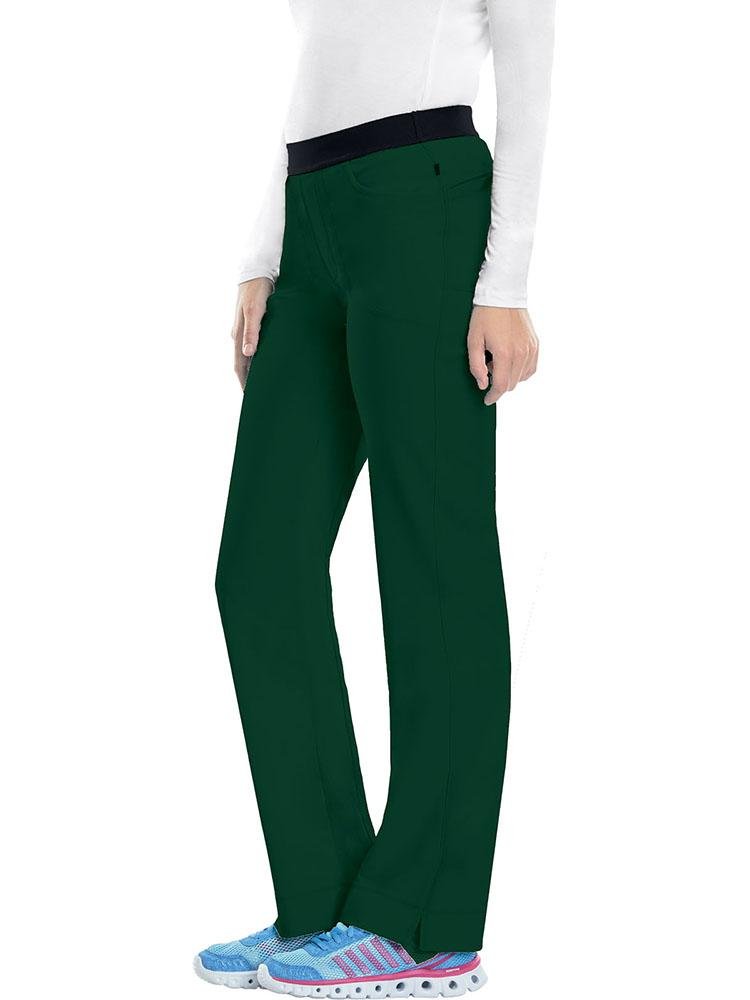 A young female Home Care Health Aid wearing a Cherokee Infinity Women's Low-Rise Slim Pull On Scrub Pant in Hunter size Large Petite featuring an elastic waistband.