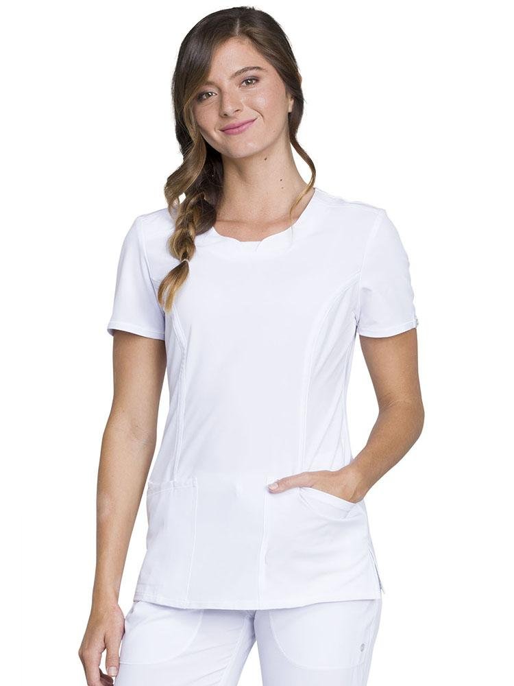 A young female Nursing Student wearing a Cherokee Infinity Women's Round Neck Scrub Top in White size Medium featuring a contemporary fit & short sleeves.