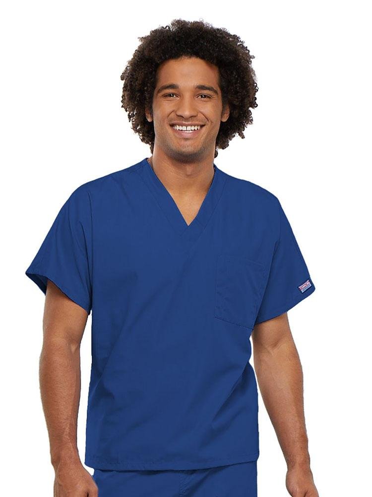 A young male Physician's Assistant wearing a Cherokee Workwear Originals Unisex Single Pocket V-neck Scrub Top in Royal size 4XL featuring short sleeves.