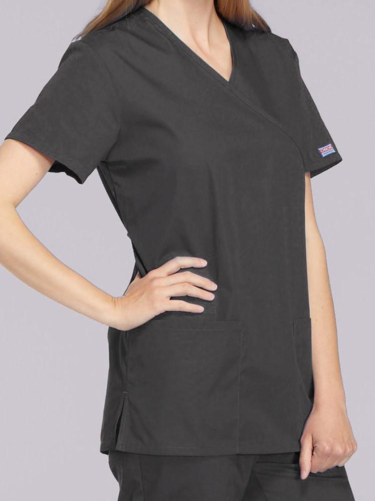 A young female Clinical Laboratory Technician wearing a Cherokee Workwear Originals Women's Mock Wrap Solid Scrub Top in Pewter size XS featuring a 2 front patch pockets.