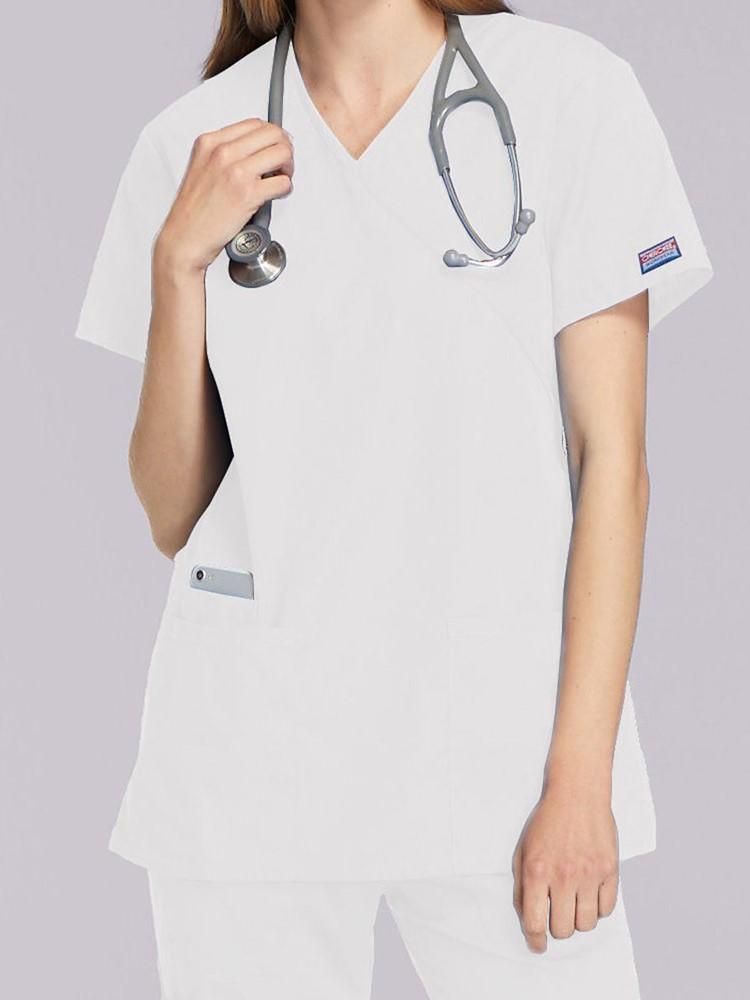 A young female Registered Nurse wearing a Cherokee Workwear Originals Women's Mock Wrap Top in White size XL featuring short sleeves.