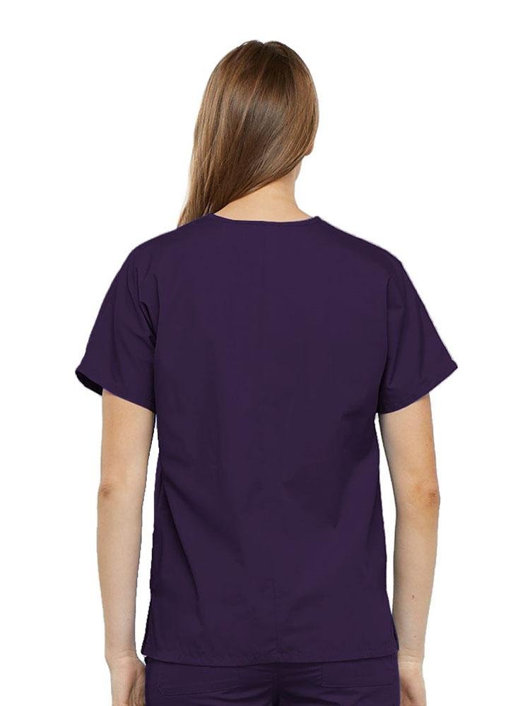 A young female Occupational Therapist wearing a Cherokee Workwear Originals Women's V-neck Scrub Top in Eggplant size medium featuring a center back length of 26.5".