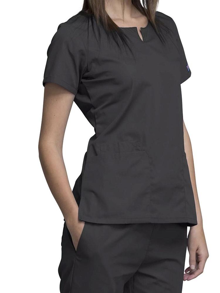 A young female Home Health Aide wearing a Cherokee Workwear Originals Women's Notch Crew Round Neck Scrub Top in Pewter size Large featuring side vents for additional range of motion throughout the day.