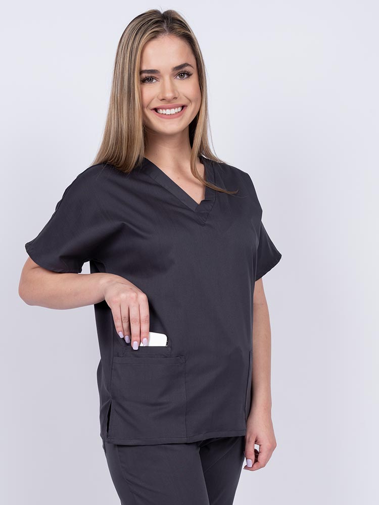 Young female healthcare worker wearing an Epic by MedWorks Unisex V-Neck Scrub Top in pewter with side slits for mobility & flair.