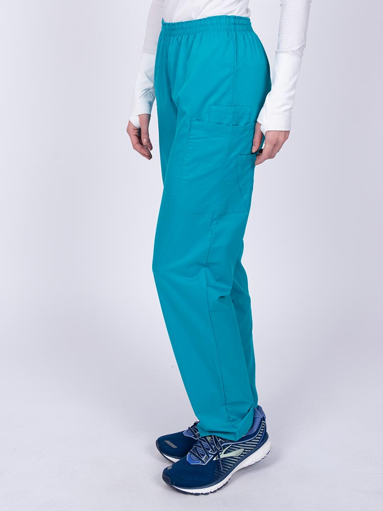 Woman wearing an Epic by MedWorks Women's Elastic Waist Scrub Pant in teal with two cargo pockets.