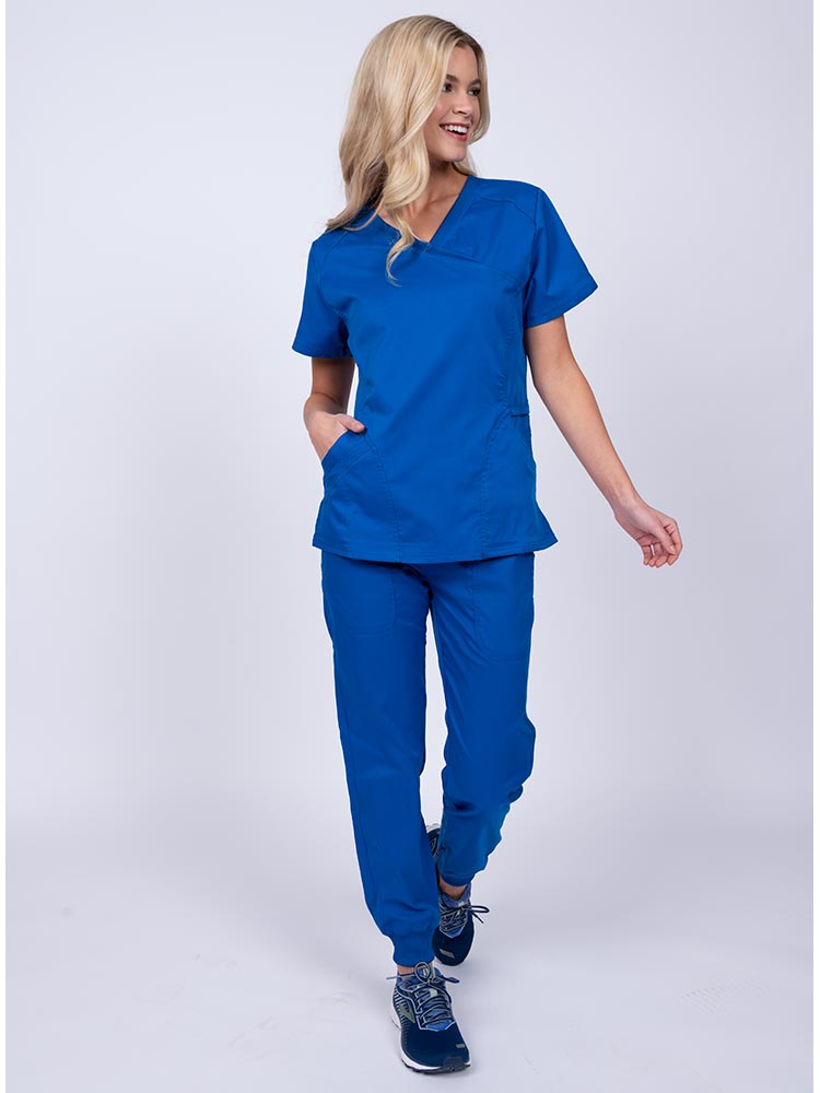 Young female healthcare worker wearing an Epic by MedWorks Women's Knit Collar Mock Wrap Scrub Top in royal featuring a 2 way stretch fabric that allows air to pass easily through the garment.