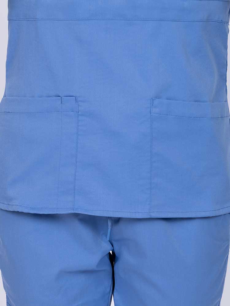 Woman wearing an Epic by MedWorks Women's Mock Wrap Scrub Top in ceil featuring two front patch pockets.