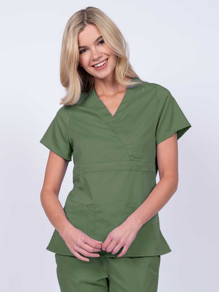 Young woman wearing an Epic by MedWorks Women's Mock Wrap Scrub Top in olive with a unique fabric content of 77% Polyester, 21% Viscose, 2% Spandex.
