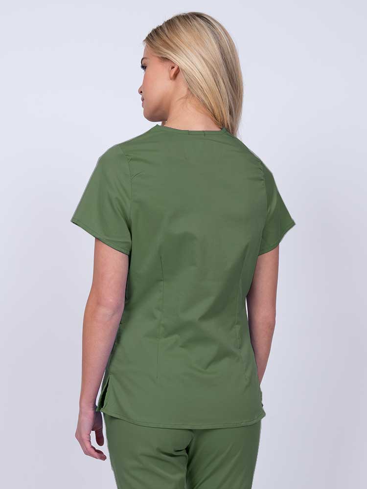 Nurse wearing an Epic by MedWorks Women's Mock Wrap Scrub Top in olive with side slits for additional range of motion.
