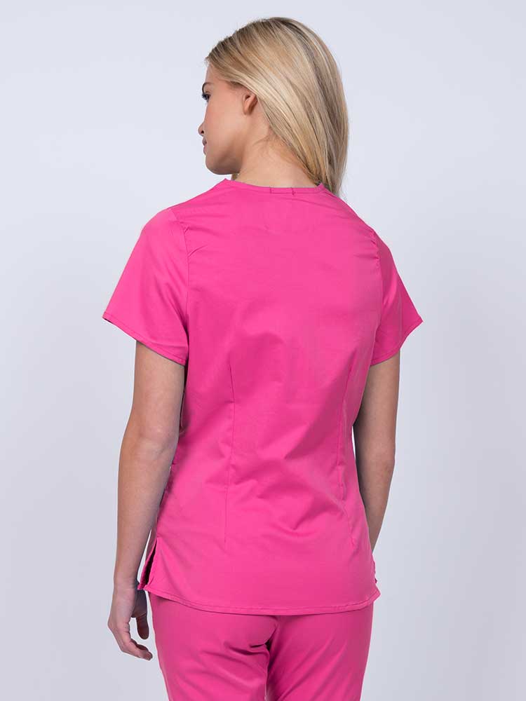 Nurse wearing an Epic by MedWorks Women's Mock Wrap Scrub Top in shocking pink with side slits for additional range of motion.