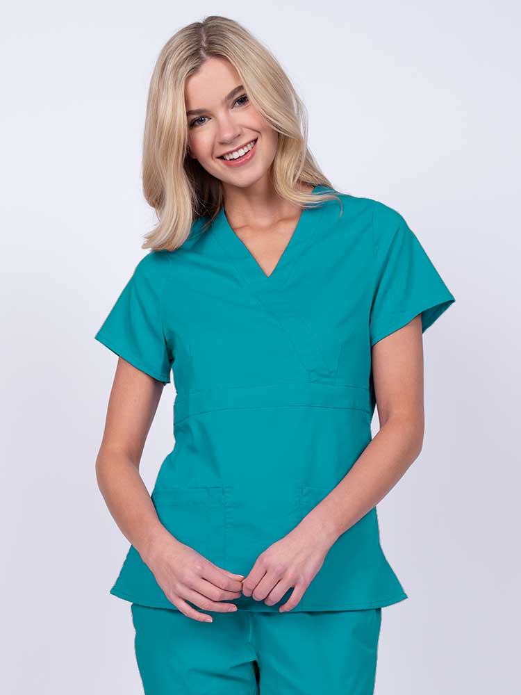 Young woman wearing an Epic by MedWorks Women's Mock Wrap Scrub Top in teal with a unique fabric content of 77% Polyester, 21% Viscose, 2% Spandex.