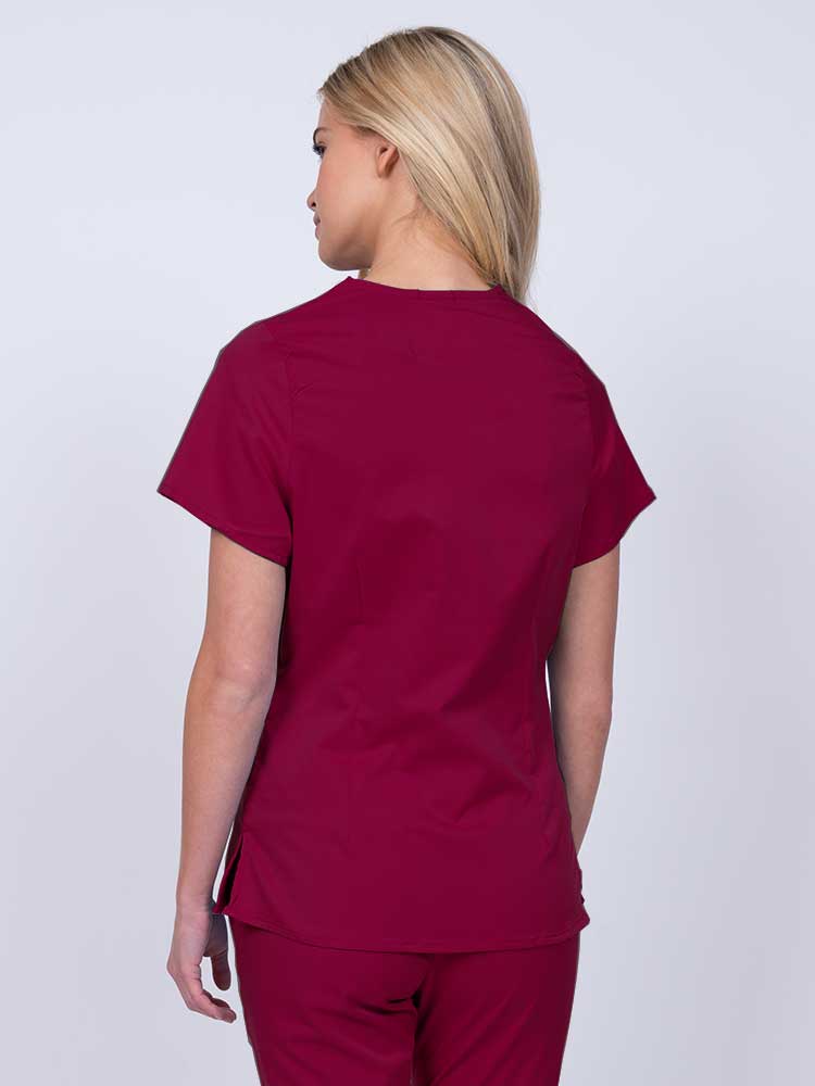 Nurse wearing an Epic by MedWorks Women's Mock Wrap Scrub Top in wine with side slits for additional range of motion.