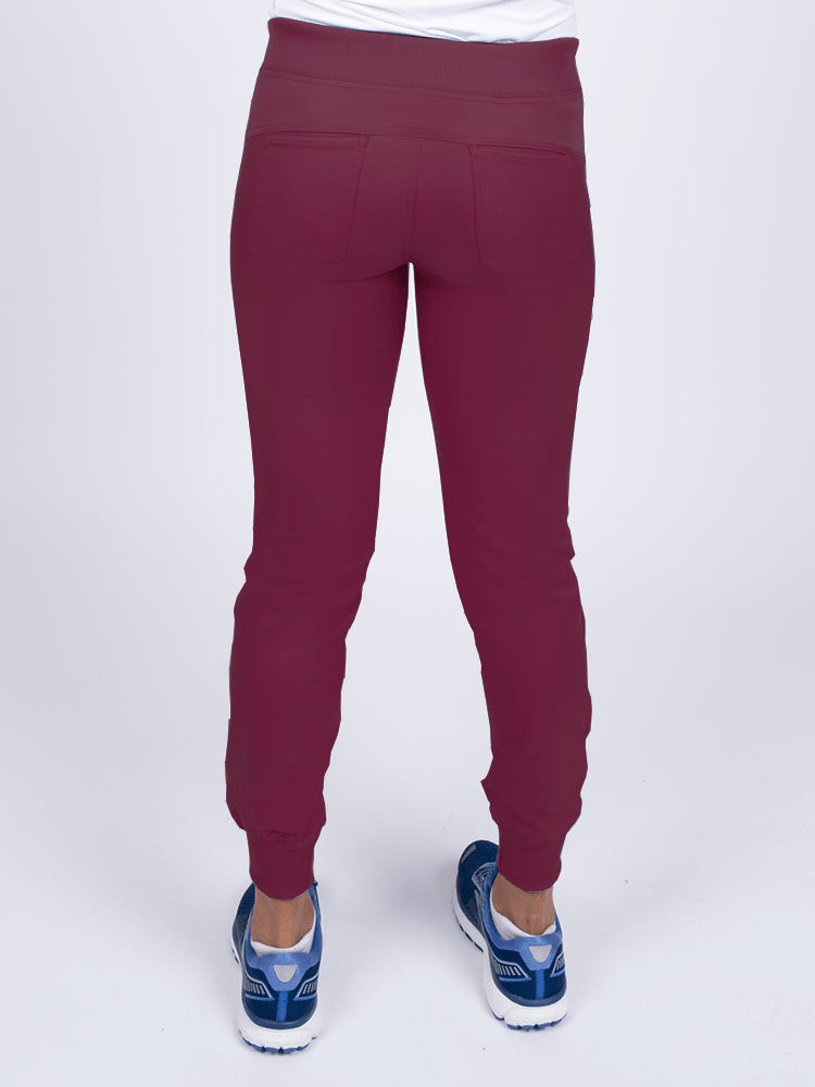 A young female Nurse Practitioner wearing an Epic by MedWorks Women's Yoga Jogger Scrub Pant in Wine  size small featuring 2 back patch pockets.