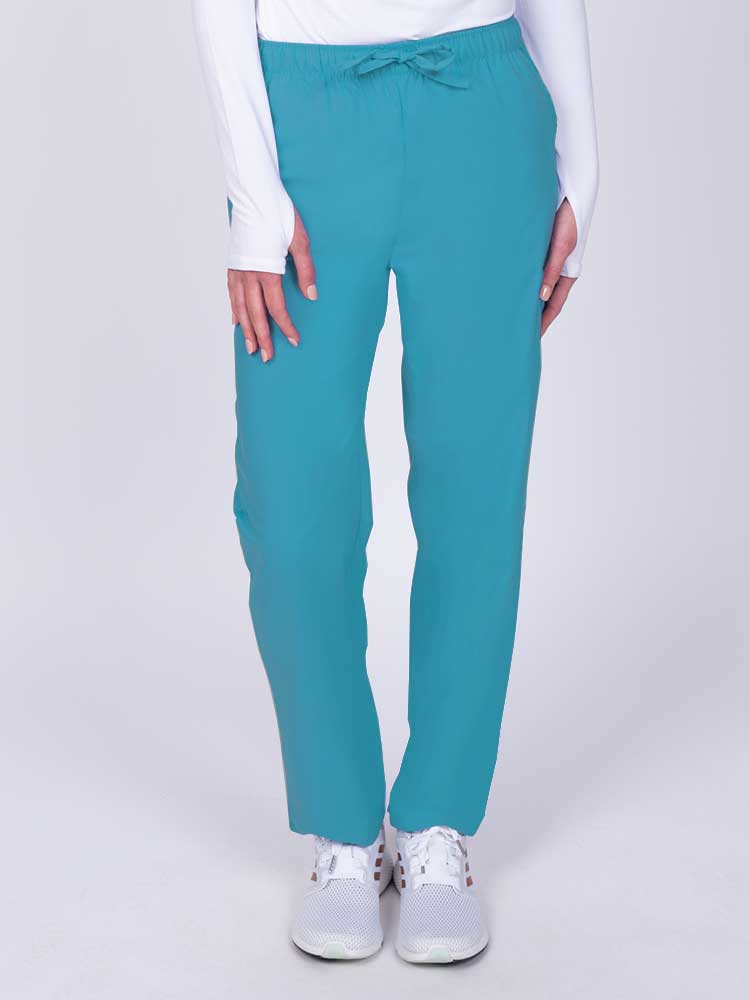 Young woman wearing a Luv Scrubs by MedWorks Women's Elastic Waist Cargo Pant in turquoise featuring one cargo pocket on the wearer's left side.