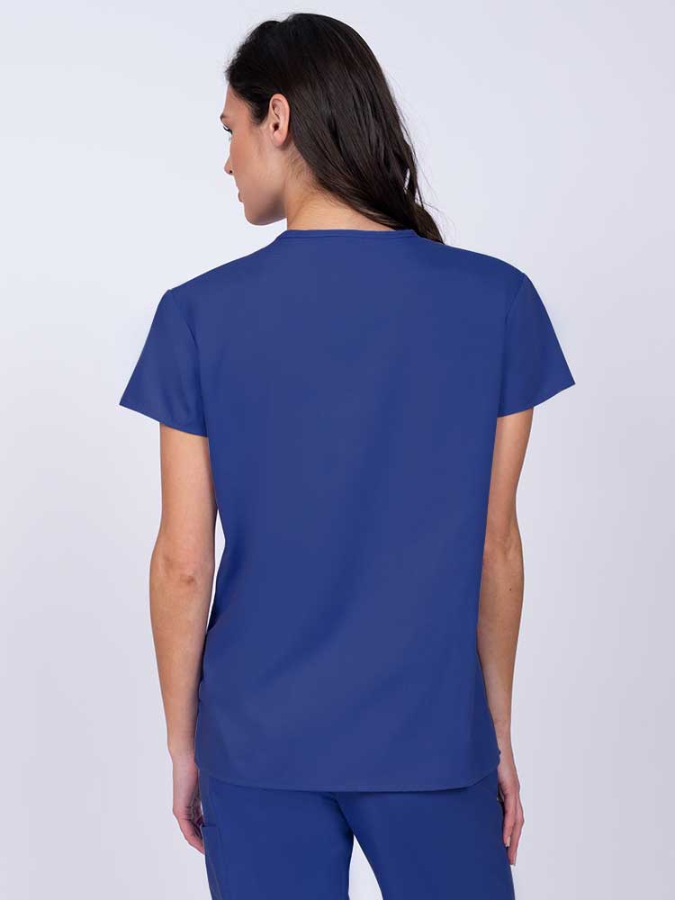 Nurse wearing a Luv Scrubs by MedWorks Women's Mock Wrap Scrub Top in royal with shoulder yokes to ensure a flattering fit.