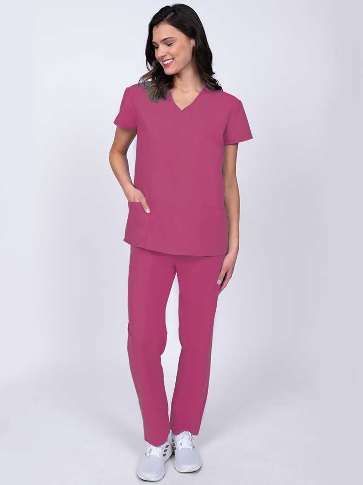 Young healthcare worker wearing a Luv Scrubs by MedWorks Women's Mock Wrap Scrub Top in shocking pink with 2 front patch pockets.