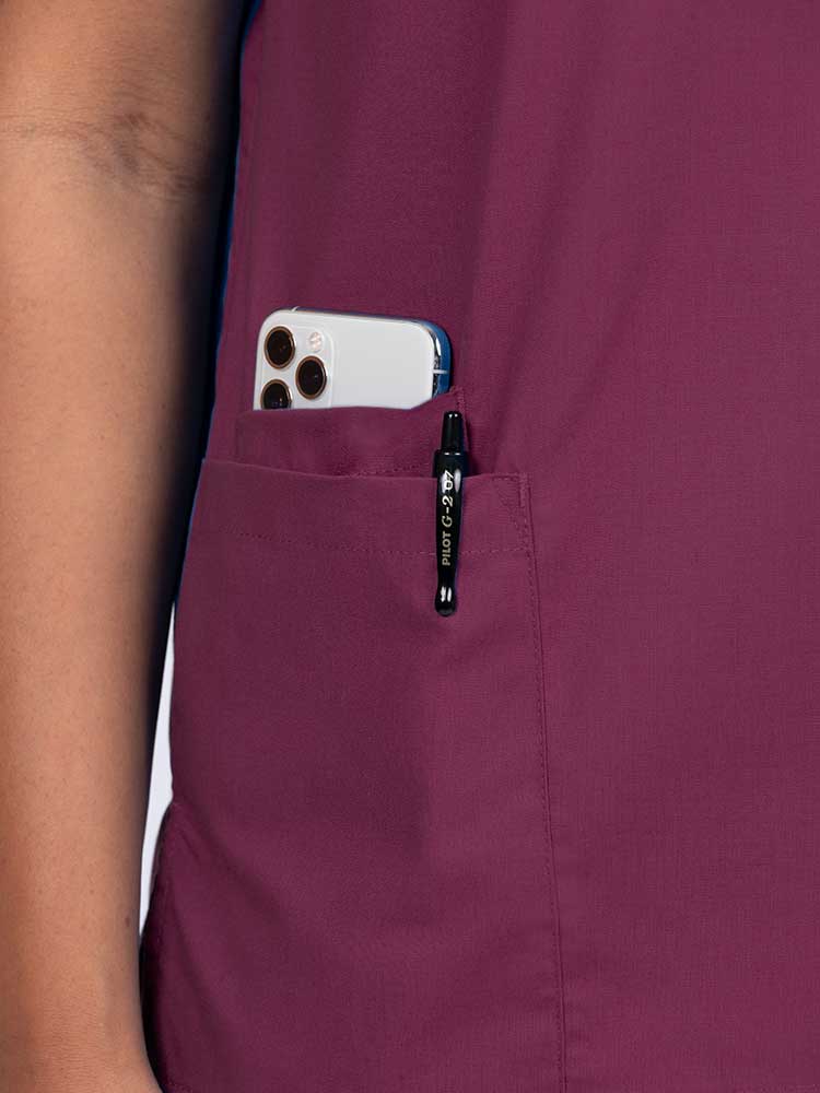 A close up look at the right side pocket on the Luv Scrubs by MedWorks Women's V-neck Scrub Top in WIne featuring an interior cell phone pocket.