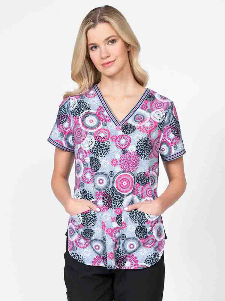 Young healthcare professional wearing a Meraki Sport Women's Print Scrub Top in "Raspberry Splash" featuring stretch side panels for a comfortable all day fit.